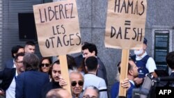 FILE - A woman holds a placard reading "Hamas=DAESH" and "free the hostages" during a tribute to the victims of the Hamas-organized attacks in Israel, at the European Parliament in Brussels, on October 11, 2023. 