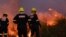 FILE - Firefighters work to extinguish a fire in Pringle Bay, as firefighters remain on high alert amid dry, hot, and windy weather in Western Cape, South Africa, January 30, 2024.