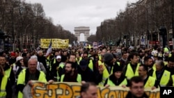 FILE - Yellow Vests protesters march on the Champs Elysees avenue in Paris. France's yellow vest protesters remain a force to be reckoned with five months after their movement started, and as President Emmanuel Macron announces his responses to their grievances, March 2, 2019.