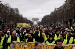 FILE - Yellow Vests protesters march on the Champs Elysees avenue in Paris. France's yellow vest protesters remain a force to be reckoned with five months after their movement started.