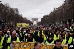 FILE - Yellow Vests protesters march on the Champs Elysees avenue in Paris.