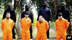 This undated image released by a militant website, which has been verified and is consistent with other AP reporting, shows members of the Islamic State group as they prepare to kill men who were allegedly spying for the U.S.-led coalition in the province of Salah al-Din, Iraq. 