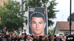 Seorang pendukung Juventus memegang spanduk bergambar Cristiano Ronaldo di depan pusat kesehatan Juventus, di Stadion Alliance, Torino, Italia, 16 Juli 2018. (Foto: AFP)
