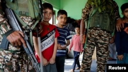 Kashmiri children stand with Indian security personnel inside a polling station, ahead of the second part of assembly elections, in Srinagar.