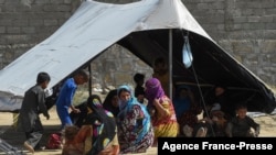 FILE - Afghan refugees sit around a makeshift tent shelter on the outskirts of Quetta, Pakistan on Sept. 6, 2021. 