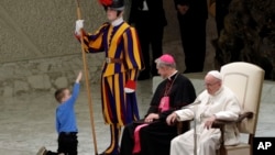 A child plays with a Swiss guard in the Paul VI Hall at the Vatican, Wednesday, Nov. 28, 2018. Pope Francis has praised the freedom, albeit undisciplined, of a hearing-impaired child who climbed onto the stage during his general audience to play.