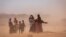 FILE - Women and children walk amidst strong dusty winds near Sagalo village in the Korahe zone of the Somali region of Ethiopia, Jan. 21, 2022. 