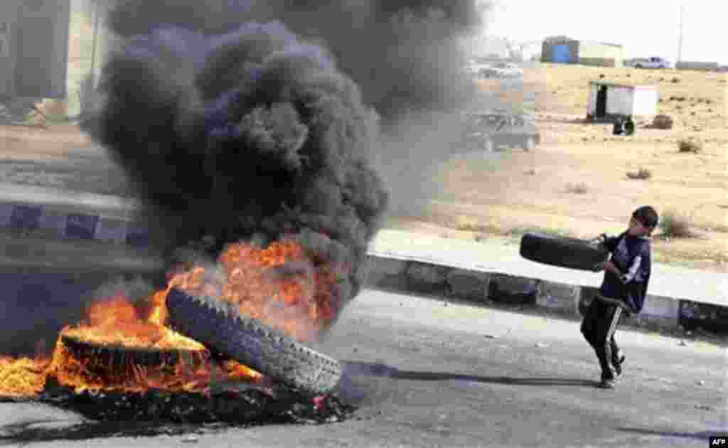 In this photo taken Wednesday, Jan. 26, 2011 and made available Thursday, Jan. 27, 2011, a young boy carries a tyre to add to a burning barricade in Sheikh Zuweid, near El-Arish, in Egypt. Egypt's ruling party said Thursday it was ready for a dialogue wit