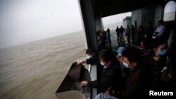 在上海附近的一场海葬仪式中，有人把父母和祖母的骨灰撒进海里
