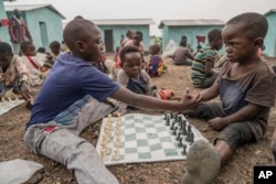 Los niños se dan la mano antes de jugar una partida de ajedrez en el Club de Ajedrez Soga del campamento de desplazados internos en Kanyaruchinya, República Democrática del Congo, el 29 de julio de 2024.