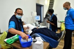 FILE - Aubrey Dhanraj, a plasma donor, lies on reclining seat to give convalescent plasma for coronavirus treatment at a newly opened plasma donor center in Twickenham, southwest London, June 11, 2020.