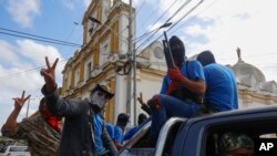 FILE - Armed pro-government militia members flash victory signs as they occupy the Monimbo neighborhood of Masaya, Nicaragua, July 18, 2018. 