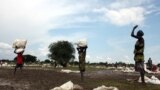 FILE - Internally displaced people carry relief food from a distribution by the World Food Program, near the town of Nyal, in South Sudan, Aug. 19, 2018.