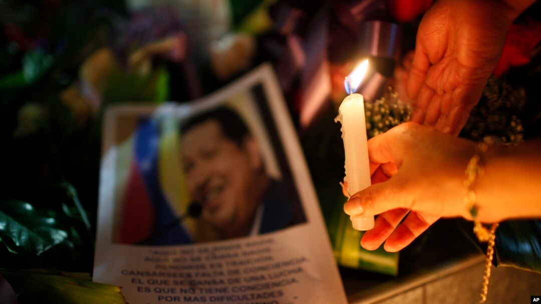 Uma mulher coloca uma vela junto a uma imagem do presidente venezuelano Hugo Chávez 