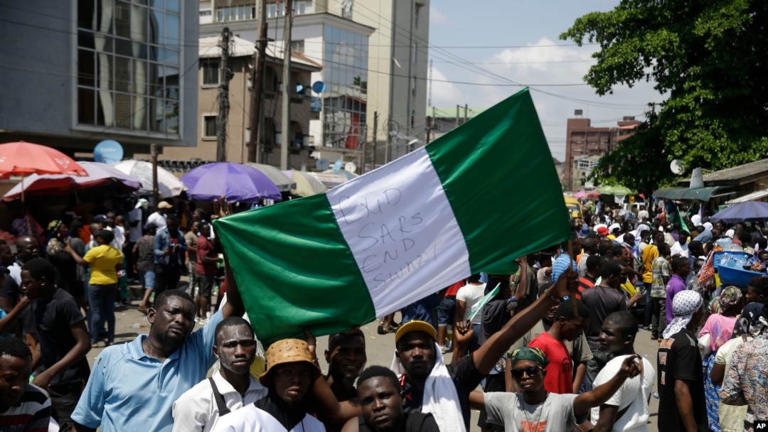 Orang-orang memegang spanduk saat mereka berdemonstrasi di jalan untuk memprotes kebrutalan polisi, di Lagos, Nigeria, Selasa, 20 Oktober 2020. (Foto: AP)