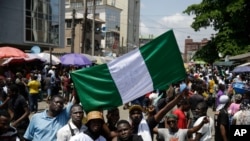 Orang-orang memegang spanduk saat mereka berdemonstrasi di jalan untuk memprotes kebrutalan polisi, di Lagos, Nigeria, Selasa, 20 Oktober 2020. (Foto: AP)