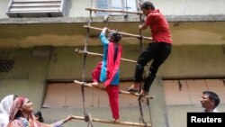 Garment workers from textile company Envoy Group demonstrate climbing a makeshift ladder, which serves as a fire exit to the building, during a protest in Dhaka, June 10, 2013. 