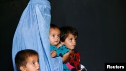 FILE - An Afghan family, returning from Pakistan, watch a short video clip about mines during a mines and explosives awareness program at a United Nations High Commissioner for Refugees (UNHCR) registration centre in Kabul, Sept. 27, 2016. 