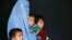 FILE - An Afghan family, returning from Pakistan, watch a short video clip about mines during a mines and explosives awareness program at a United Nations High Commissioner for Refugees (UNHCR) registration centre in Kabul, Sept. 27, 2016. 