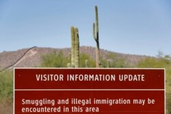An uphill section of the international border wall that runs through Organ Pipe National Monument is shown above a park warning sign, Aug. 22, 2019 in Lukeville, Ariz.