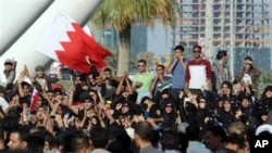 Demonstrators wave Bahraini flags, cheer, and throw confetti, under the Pearl Monument on a main square in Manama, Bahrain, February 15, 2011