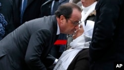 Le président français François Hollande embrasse la mère du défunt policier Ahmed Merabet cours des commémorations à Paris, mardi 5 janvier 2016.