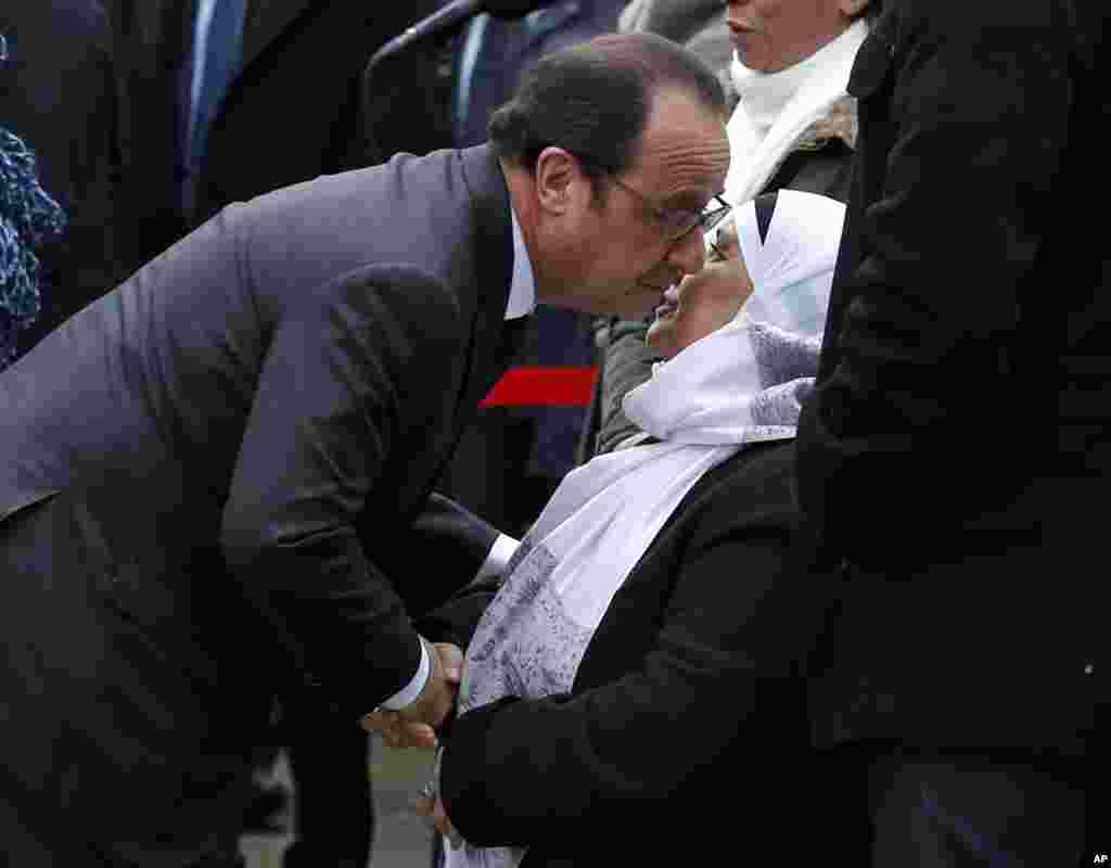 French President Francois Hollande kisses late police officer Ahmed Merabet's mother during commemorations in Paris, Tuesday Jan. 5, 2016.