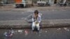 A child sits along a road median as he eats his breakfast of a single piece of "roti" (South Asian bread) while waiting for work in Karachi early morning May 6, 2012.