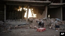 FILE - A man selling chicken sits in an area recently retaken by U.S.-backed Syrian Democratic Forces (SDF) from Islamic State militants in Hajin, Syria, Feb. 16, 2019.