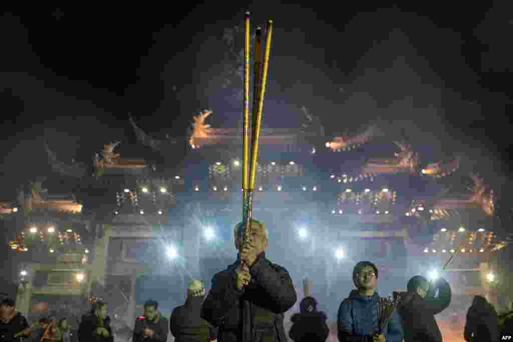 People pray with incense sticks to celebrate the Lunar New Year, marking the Year of the Dog, at the Longhua temple in Shanghai.