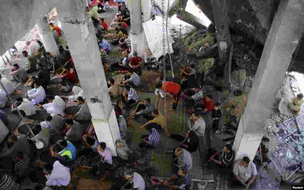 Palestinians attend Friday prayers conducted among the ruins of a mosque that was hit by an air strike in Rafah, Aug. 22, 2014. 