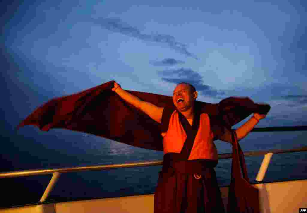 August 3: Buddhist monk Geshe Tenley laughs on the bow of a boat during the release of lobsters back into the ocean on "Chokhor Duchen", or the anniversary of Buddha's turning of the Dharma Wheel, in the waters off Gloucester, Massachusetts. Buddhists pra