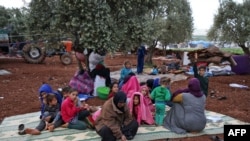 FILE - Displaced Syrians gather in a field near a camp for displaced people in the village of Atme, in the jihadist-held northern Idlib province, May 8, 2019.