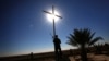 FILE - A member of the Babylon Brigades stands beneath a cross in the town of Khidr Ilyas, southeast of Mosul, Nov. 22, 2016.