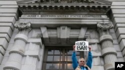 FILE - A protester holds up a sign outside of the 9th U.S. Circuit Court of Appeals in San Francisco, Feb. 7, 2017. 