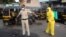 A civic worker sprays disinfectant on a policeman standing guard after a protest by migrant workers against the extension of the lockdown, in a slum in Mumbai, India, April 14, 2020. 