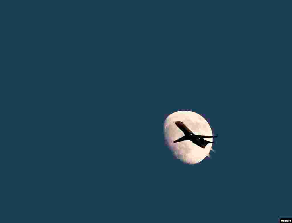 An airplane is seen agains the moon in its waxing gibbous phase in the sky over Hoboken, New Jersey, USA, June 19, 2013. On Sunday, June 23, a perigee moon will coincide with a full moon when it will pass by the earth at its closest point. 