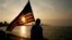 Un estudiante mexico-estadounidense que estudia en Cuba observa el atardecer en el Malecón de La Habana, ondeando una bandera de Estados Unidos.