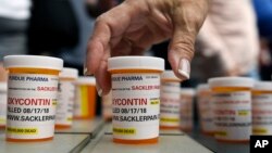 FILE -Family and friends who have lost loved ones to OxyContin and opioid overdoses leave pill bottles in protest outside the headquarters of Purdue Pharma, which is owned by the Sackler family, in Stamford, Conn., Aug. 17, 2018.