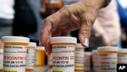 FILE -Family and friends who have lost loved ones to OxyContin and opioid overdoses leave pill bottles in protest outside the headquarters of Purdue Pharma, which is owned by the Sackler family, in Stamford, Conn., Aug. 17, 2018.