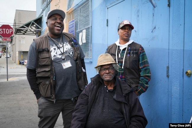 Homeless resident Larry James Bell, seated, is seen with Ventrell Johnson, left, and Jonice Pauley of the San Francisco Homeless Outreach Team, Tuesday, Sept. 10, 2024, in San Francisco. (AP Photo/Terry Chea)