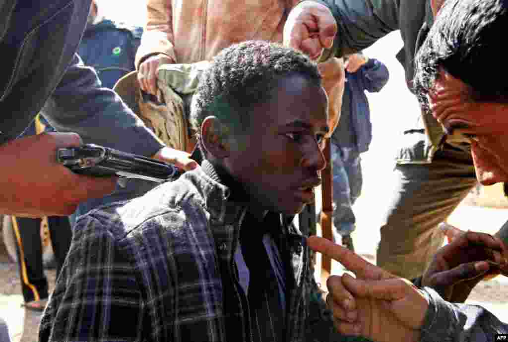 Rebels hold a young man at gunpoint, who they accuse of being a loyalist to Libyan leader Muammar Gaddafi. (Reuters/Goran Tomasevic)