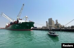 Sebuah kapal penjaga pantai berlayar melewati kapal kontainer komersial yang berlabuh di pelabuhan Laut Merah Hodeidah yang dikuasai Houthi, di Hodeidah, Yaman, 25 Februari 2023 .(Foto: Reuters)