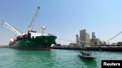 Sebuah kapal penjaga pantai berlayar melewati kapal kontainer komersial yang berlabuh di pelabuhan Laut Merah Hodeidah yang dikuasai Houthi di Hodeidah, Yaman, 25 Februari 2023 .(Foto: Reuters)