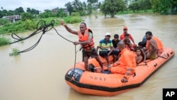 Un equipo de la Fuerza Nacional de Respuesta a Desastres (NDRF) lleva personas a un lugar seguro a través de zonas inundadas tras aguaceros en Agartala, en el estado nordeste de Tripura, en India, el jueves 22 de agosto de 2024. 