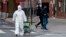 Žena u zaštitnom odijelu izlazi iz prodavnice u New Yorku (Foto: AFP/Johannes Eisele)