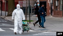 یک زن با لباس سرتا پا محافظ با سبد خرید در شهر کوئینز، نیویورک