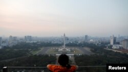 A girl looks on National Monument (Monas) as smog covers the capital city of Jakarta, Indonesia, July 4, 2019. 