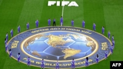 2026 월드컵 경기가 열리는 구장에서 FIFA 자원봉사자들이 공식 메달 배너 주변에 모여있다.