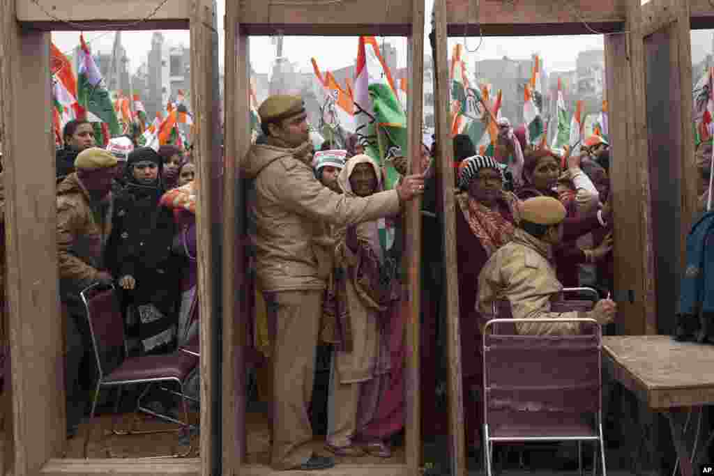 India&#39;s opposition Congress party supporters wait to enter the rally ground as policemen wait beside security gates during an election campaign rally ahead of Delhi state election in New Delhi.